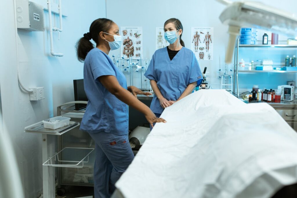 Medical professionals in scrubs and masks discussing in a clinical environment.