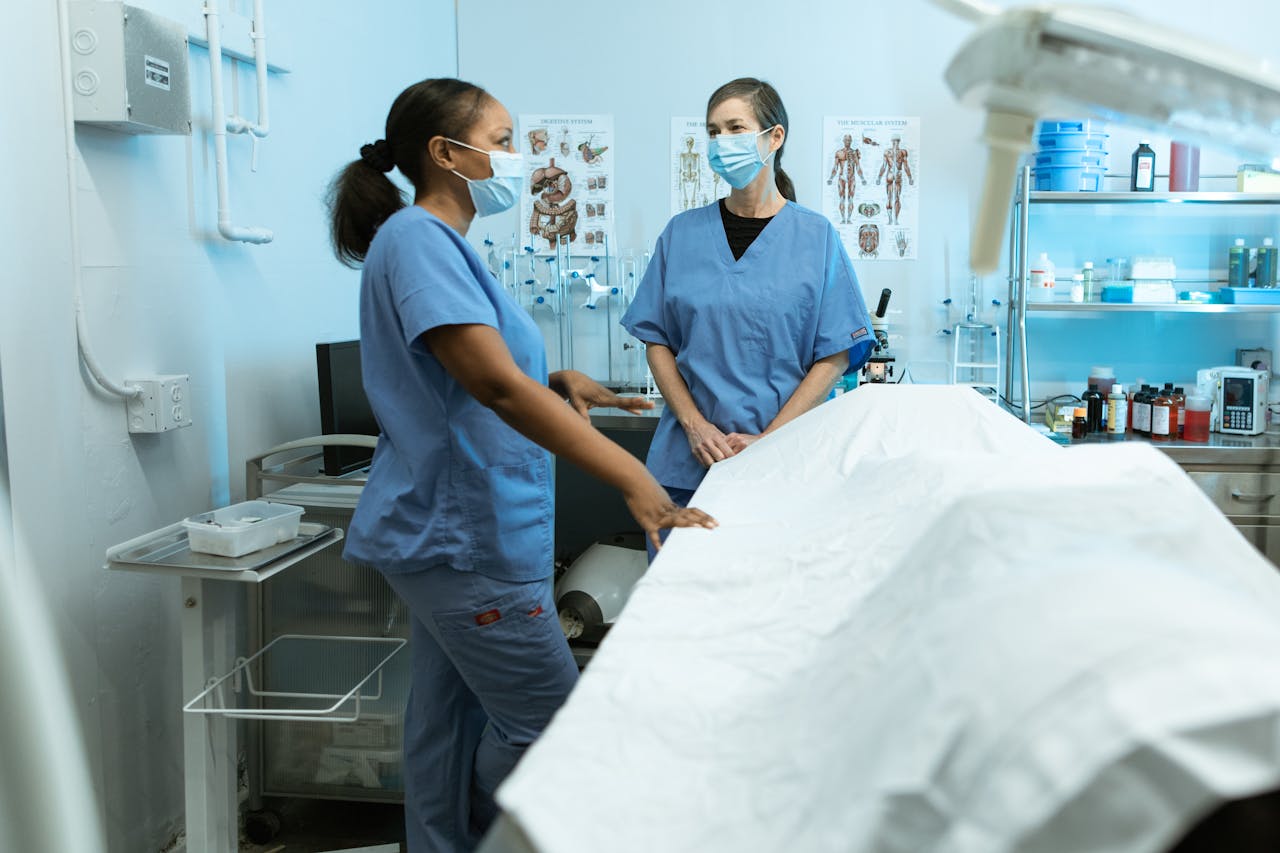 Medical professionals in scrubs and masks discussing in a clinical environment.